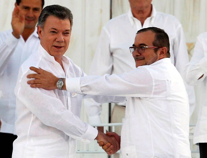 Colombian President Juan Manuel Santos and Marxist rebel leader Rodrigo Londono Echeverri of FARC, the Revolutionary Armed Forces of Colombia, shake hands Sept. 26 in Bogota. (CNS photo/John Vizcaino, Reuters)