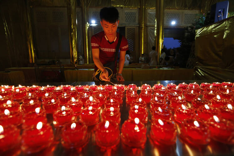 A person lights a candle for explosion victims at the Chaoyin Temple Aug. 14. The Aug. 12 blast engulfed an industrial area where toxic chemicals and gas were stored in the northeast Chinese port city. (CNS photo/Wu Hong, EPA) 